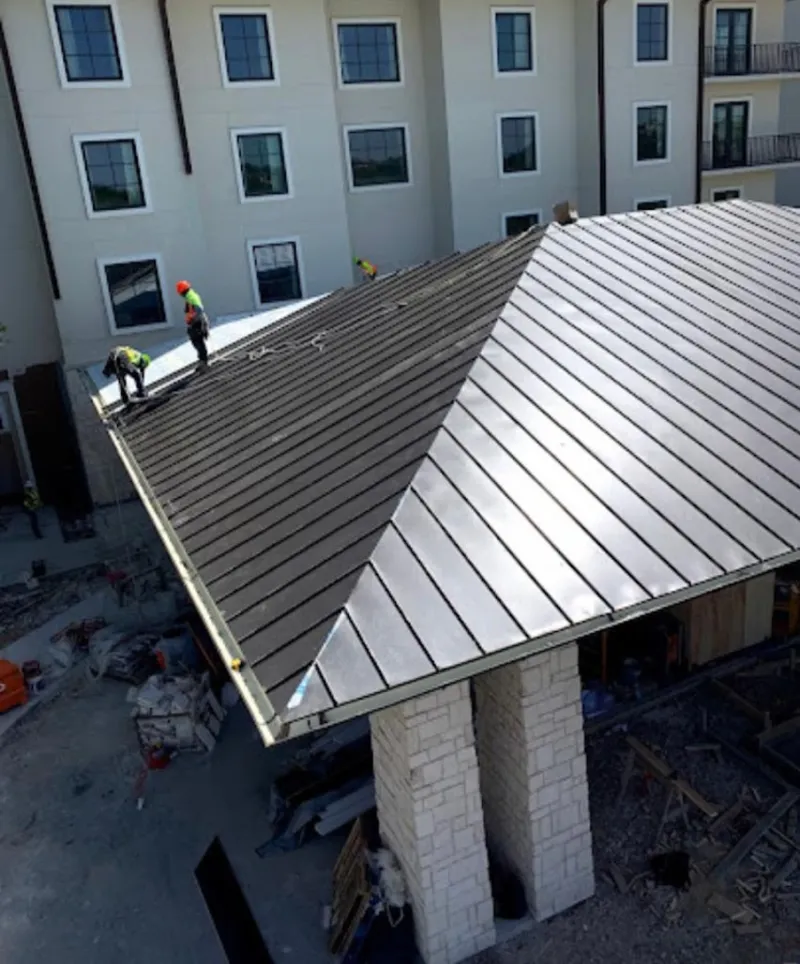 Crew installing standing seam metal roof panels on a commercial project in Middle Paxton
